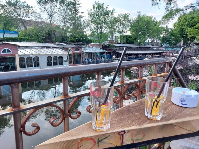 Fotografische Abbildung, die zwei leere Cocktailgläser vor einem idyllischen innerstädtischen Kanal zeigt.