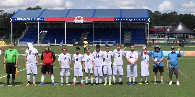 Soccer players, coaches and referee line up on soccer field.