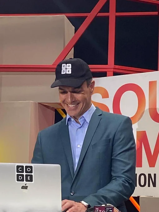 The President of the Spanish Government, Pedro Sánchez, stands at a laptop and participates in an Hour of Code.