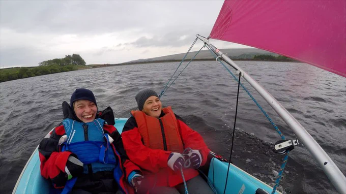 Two women in a sailing boat, smiling.