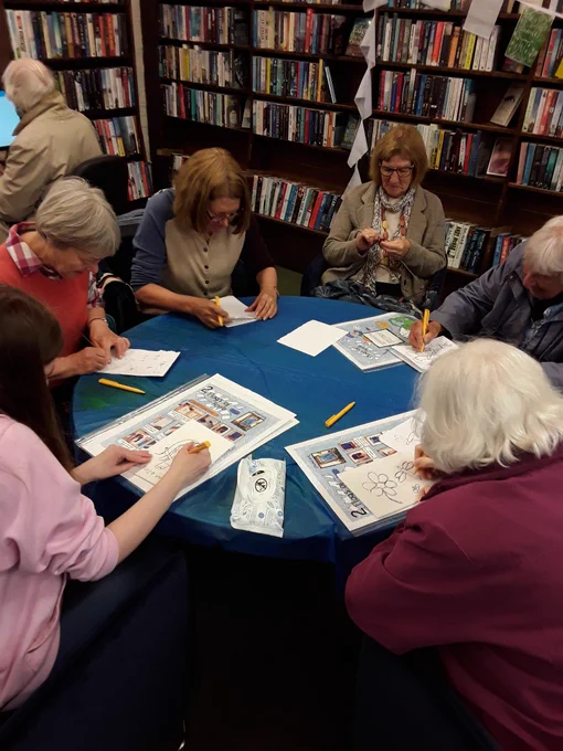 Knit and Natter group of 6 women sit round a table and design their flags 