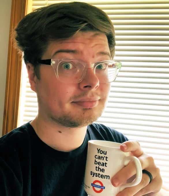 It’s Tim, with disheveled hair, holding a mug of tea with the phrase “You can’t beat the system” on the side.