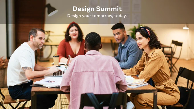 A group of five people gather around a table to work with laptops and notebooks.