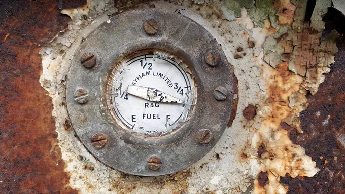 fuel dial on a train. very very rusty. all flaking. different colours of brown. 