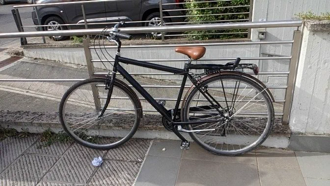 A photo of a very nice bike, leaning up against a fence.