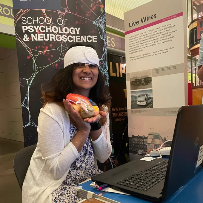 Person wearing a brain scanner and holding a brain model