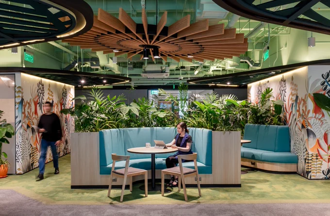 Woman sits in a booth working in a hub area 
