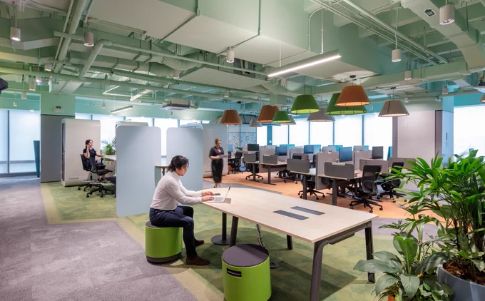 Multiple people work in different workspaces in open workspace area
