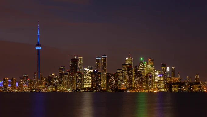 The Toronto skyline at night, as seen from Lake Ontario. The CN tower is lit blue.