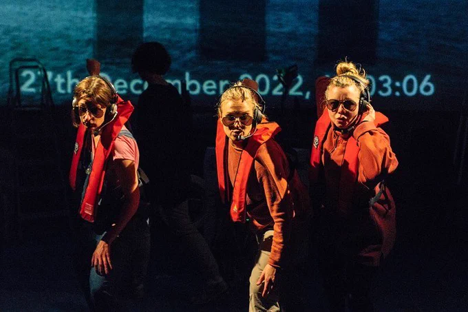 Actors Sophie Steer (Noa), Kate Shenton (Ira) and Katherine Newman (Niamh) hang onto the edge of a helicopter.