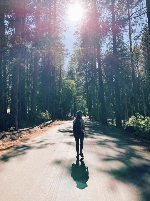 Back of a girl walking against the backdrop of a forest