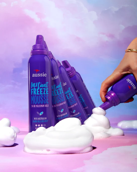 Aussie Instant Freeze Mousse leaning on cloud of dispensed mousse.
