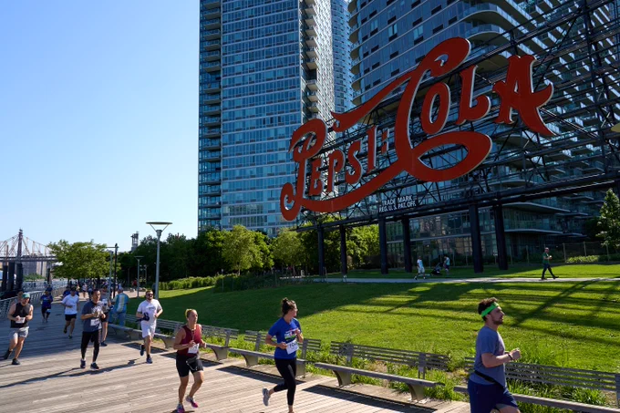 Runners in the 7th annual LIC Waterfront 5K pass the historic Pepsi-Cola sign in Gantry Plaza State Park