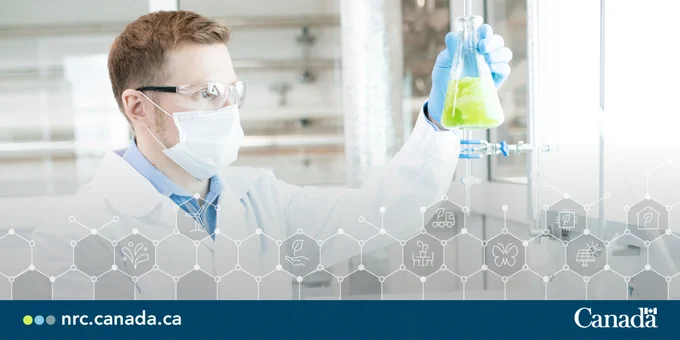 Masked scientist inspecting a yellow liquid in a beaker