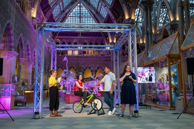 Science Together co-ordinator Rachel Ashwanden hosting a 'smoothie bike power' demonstration with two Oxfordshire Play Association representatives; with BSL interpretation (credit: John Cairns)