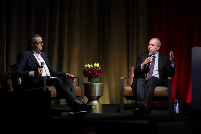 Two people sitting in chairs speaking into microphones