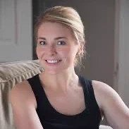 A portrait image of a smiling woman with blond hair and a black top. 