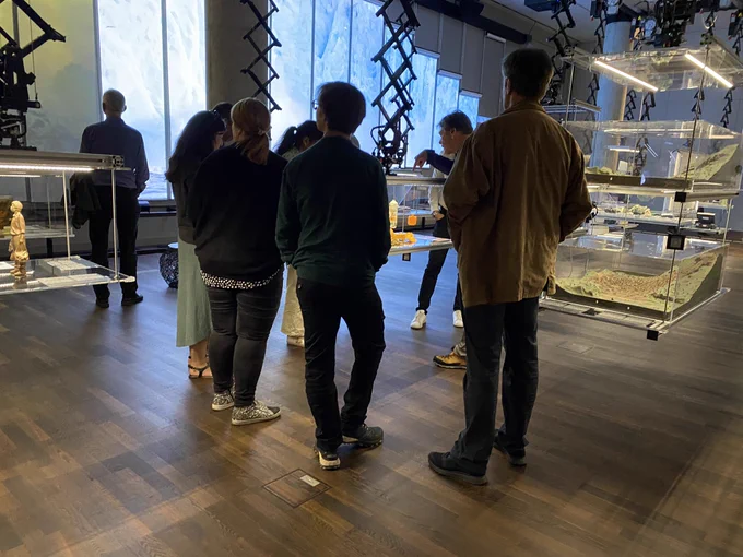 The picture shows people grouped around one of the suspended display cabinets in @HumboldtForum’s “After Nature” exhibition.