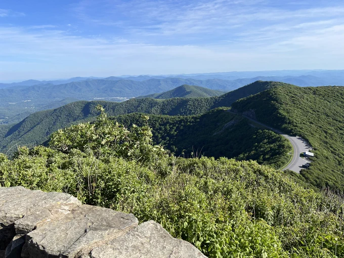 Rock wall in foreground, green mountains in background with a highway cutting through