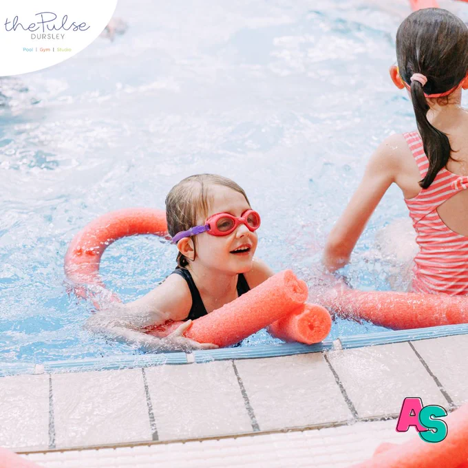 Two girls in swimming pool holding pool noodles
