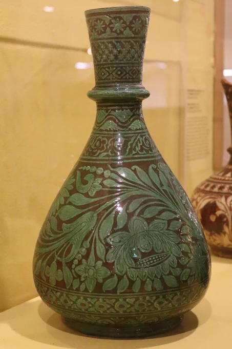 Wonderland Art Pottery (Bombay School of Art) India, Earthenware vase; scrolling floral all-over decoration painted in white slip and covered in a green glaze (c.1880-90), The Potteries Museum & Art Gallery STKMG:CER2539. Photo Credit: The Potteries Museum & Art Gallery