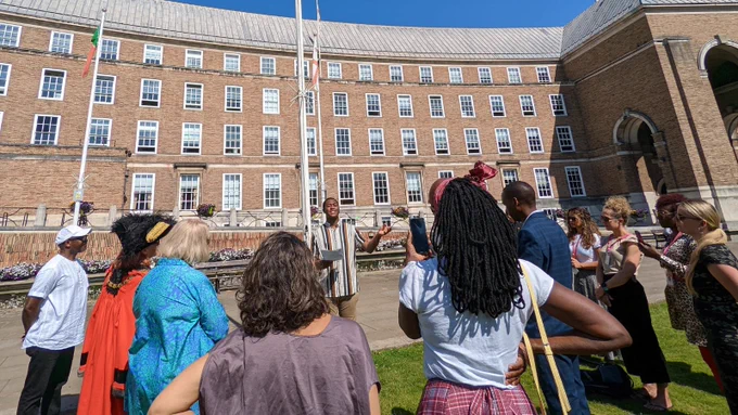 City Hall is in the background. A small crowd of people encircle Jeremiah Dom-Ogbonna, one of Bristol's Youth Mayors. He is speaking and his hand is raised in a gesture.