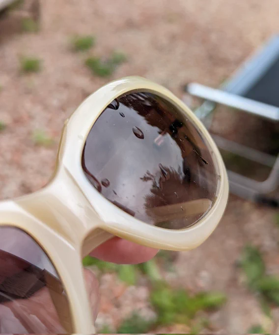 Close up of sunglasses with raindrops on the lens.