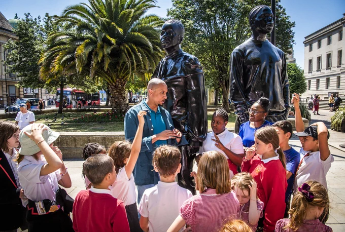 Thomas J Price in front of his new sculpture, talking to some school children about it