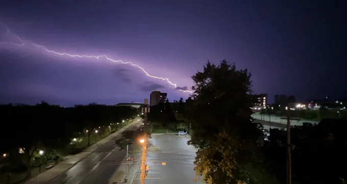 A large bolt of lightning lights up the night sky and leads down toward Michigan Stadium