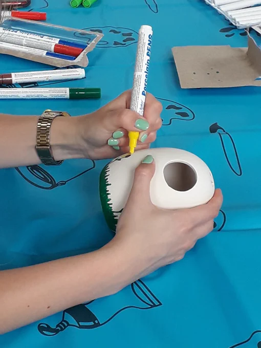 Person using porcelain pen to decorate pot