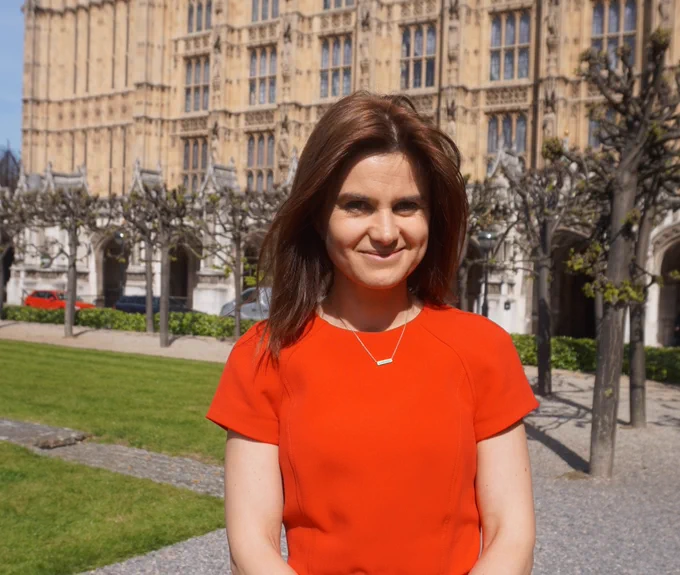 Jo Cox MP smiling, in front of the Houses of Parliament.