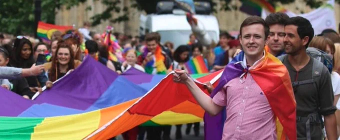 Photograph of people carrying a large rainbow flag as part of York Pride parade