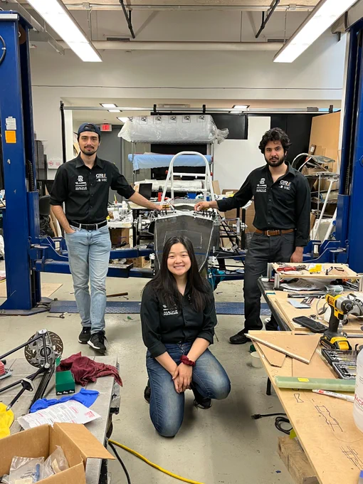 Pictured are Team Manager Deven Edison (left), Technical Director Fiona Mann (centre), and Electrical Director Joseph Caruana (right) posing with their electric racecar. 
