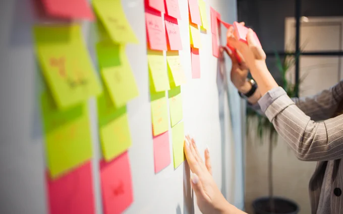 close up view of pink and green sticky notes placed on a wall