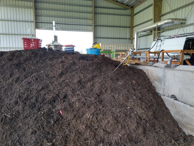 A side view of compost pile with sampling equipment on top. The mobile laboratory with advanced instrumentation is visible in the background. 