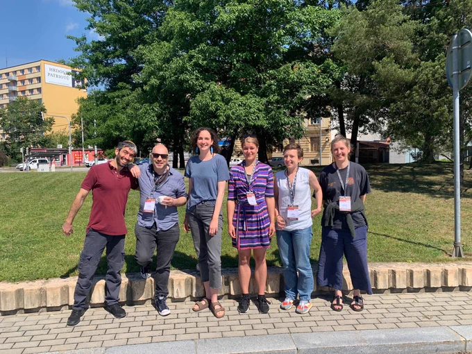 A group of confernce attendants stood in front of some trees. 