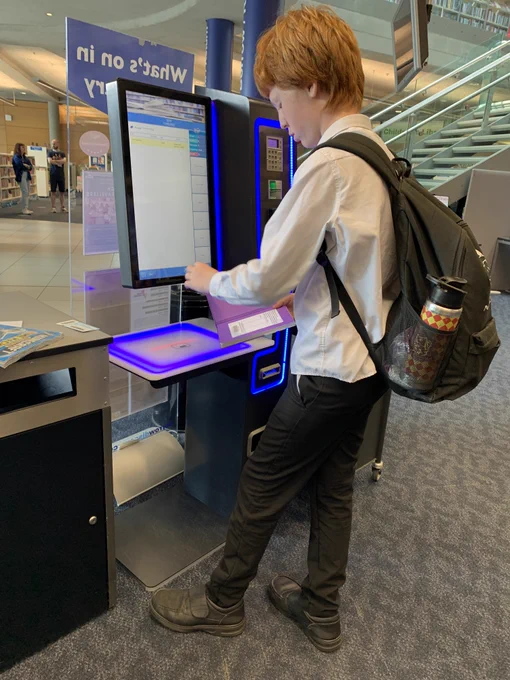 A Year 7 student uses one of the Millennium Library's automated borrowing stations to take out a book.