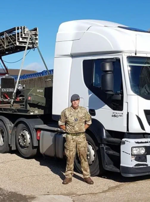 Image shows a man stood in front of truck.