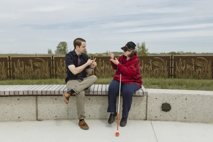 A DBCS manager and client sit outside and have a conversation using American Sign Language. 