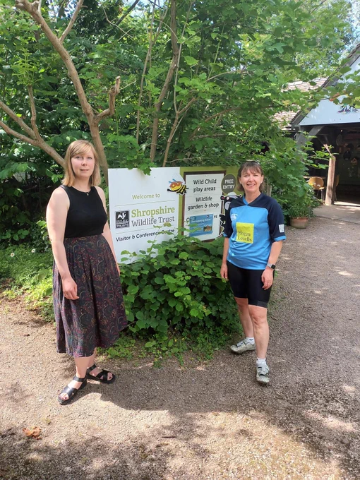 Susan and a member of Shropshire Wildlife Trust staff stood in front of a sign for the visitor centre nature reserve.