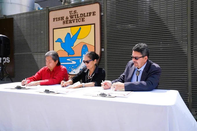Secretary Haaland, center, signs the documents to transfer the fish hatchery to the Nez Perce Tribe