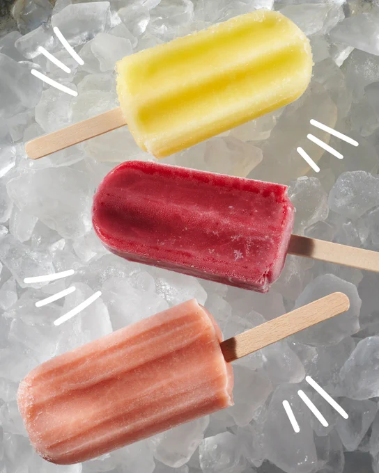 3 ice pops with wooden sticks on top of bunch of ice cubes. Each pop is a different colour & flavour - yellow, dark pink and pale orange.