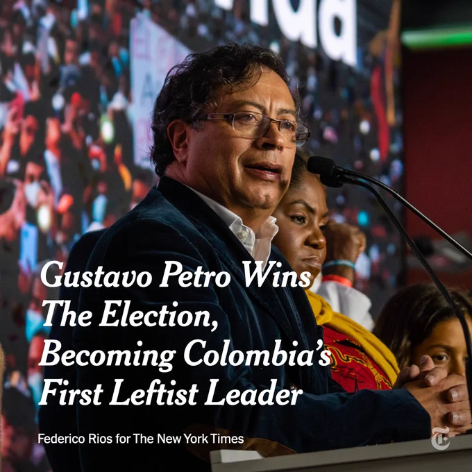 Gustavo Petro stands at a podium and speaks into a microphone at the end of the first round of Colombia's presidential elections in Bogota in May. Petro's hands are clasped and resting on the podium. Text over the image reads: Gustavo Petro wins the election, becoming Colombia's first leftist leader. Photo by Federico Rios for The New York Times.