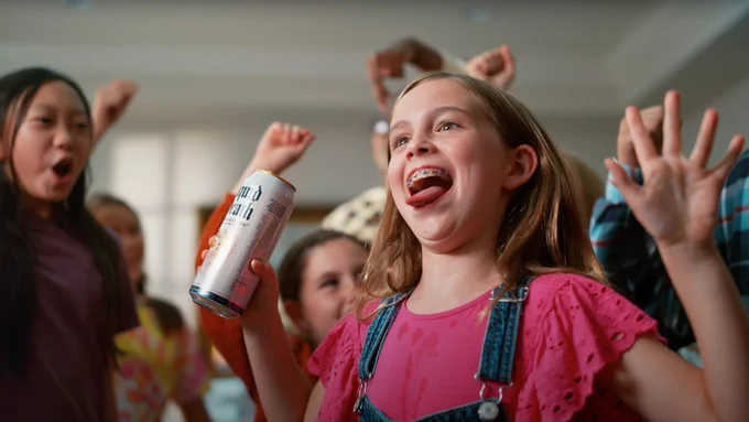 Still from 'Big Game Commercial' advertisement showing a minor holding a can of Liquid Death Mountain Water at a party.