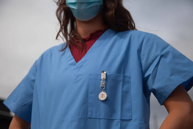 A picture of a person in scrubs wearing a mask
