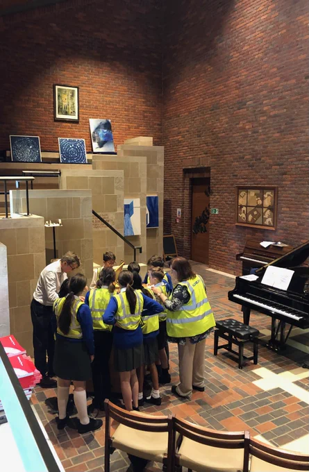 A group of Year 5 and Year 6 students stood around a chamber organ in Robinson College chapel. Dr Jeremy Thurlow stands to the right-hand side as he plays.