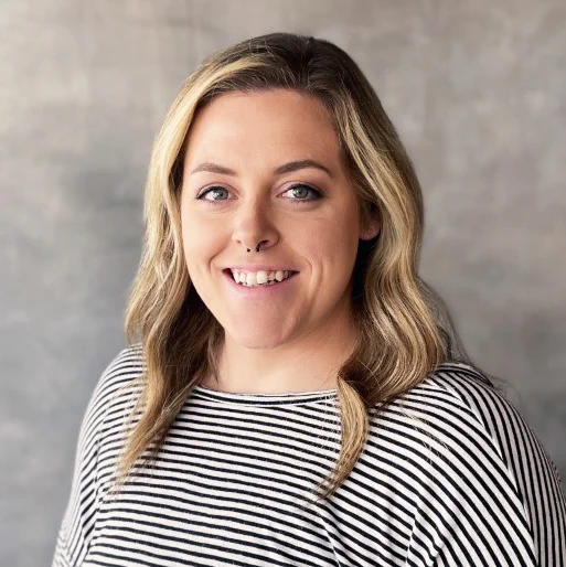 A woman smiling for a professional headshot. She is wearing a black-and-white striped shirt.