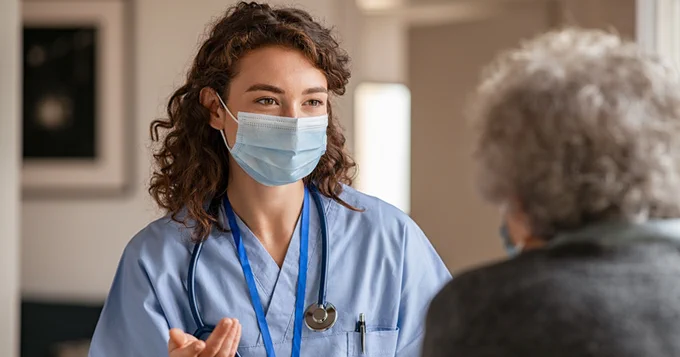 A healthcare worker speaks with a woman.