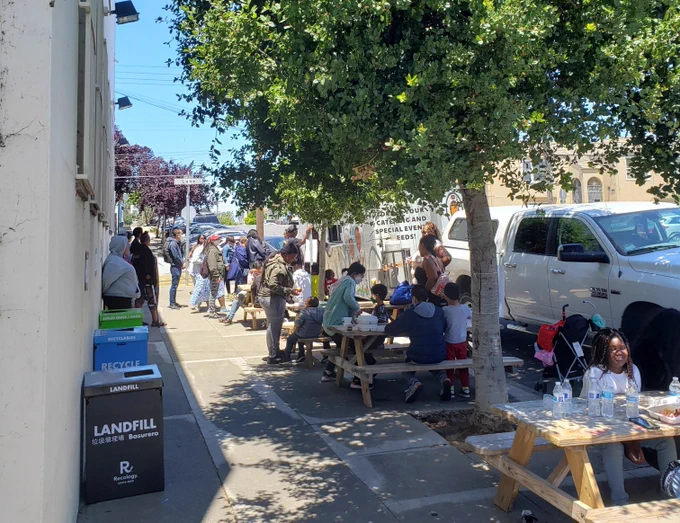A crowd at a food truck and picnic benches