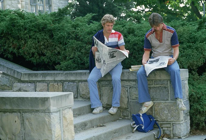 male students read newspaper on campus